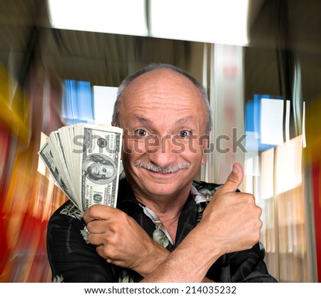 Lucky old man holding dollar bills at shopping mall