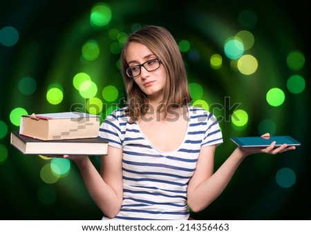 Pretty young girl  holding a book in one hand and a tablet-pc in the other