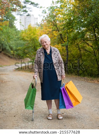 Old woman standing with shopping bags in the street