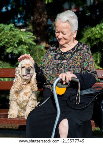 Old woman sitting on a bench with american cocker spaniel