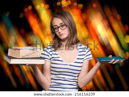 Pretty young girl  holding a book in one hand and a tablet-pc in the other on a blue background