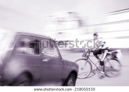 Dangerous city traffic situation with a cyclist and a car in motion blur