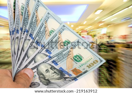 Man holding stack of dollar bills at shopping mall