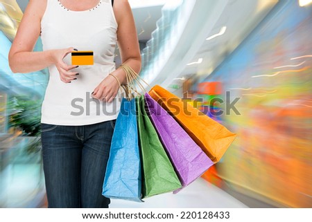 Woman holding shopping bags and credit card at shopping mall