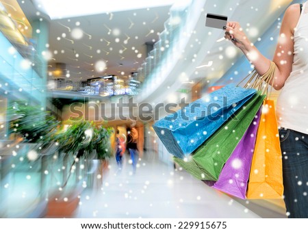 Woman holding shopping bags and credit card at shopping mall.  Christmas and holidays concept