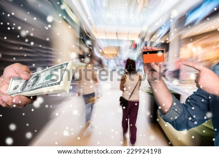 Man holding stack of dollar bills, another man holding credit card at shopping mall.  Christmas and holidays concept
