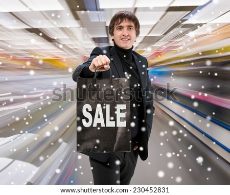 Smiling man with shopping bag at shopping mall. Christmas and holidays concept