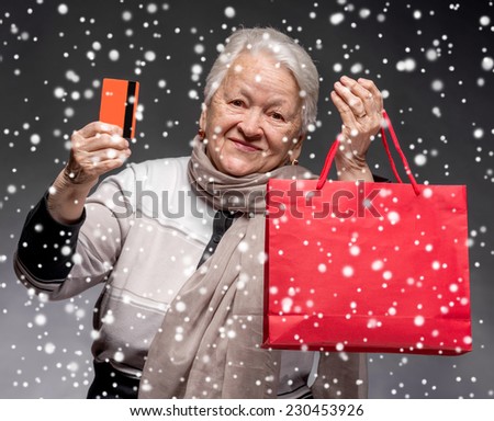 Happy old woman with shopping bags and credit card. Christmas and holidays concept