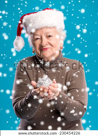 Old woman in santa hat with christmas ball. Christmas and holidays concept