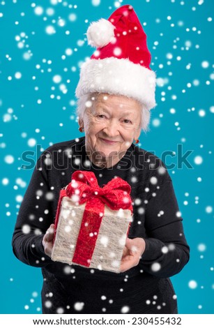 Old woman in santa hat with gift box. Christmas and holidays concept