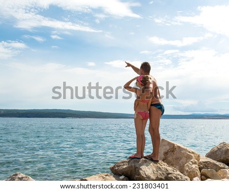Little girl and father pointing up on the beach