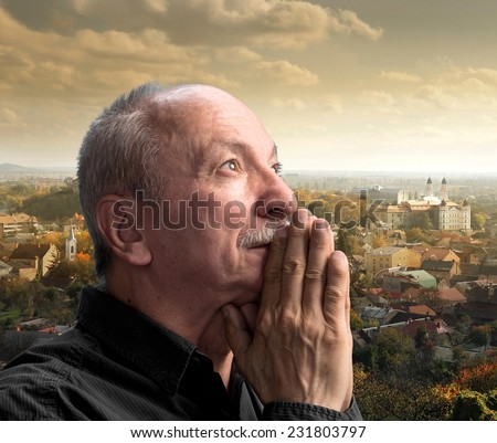 Senior man praying against cityscape