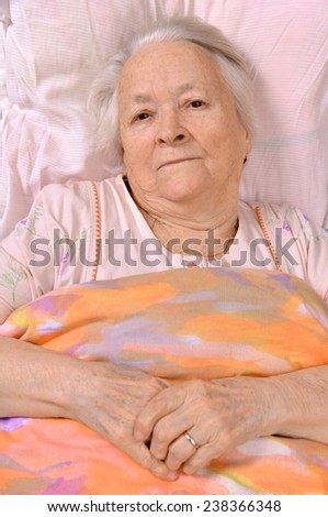 Sick old woman lying at bed