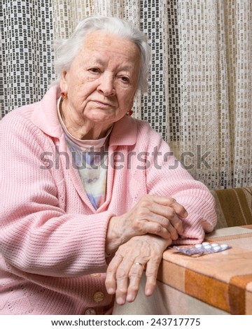 Old sad woman with pills at home.  Worried about  having to take too many pills
