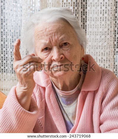 Portrait of  old woman in angry gesture at home