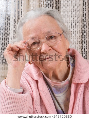 Portrait of old sad woman in glasses at home