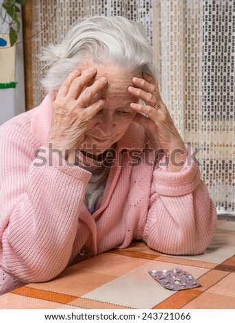 Old sad woman with pills at home.  Worried about  having to take too many pills