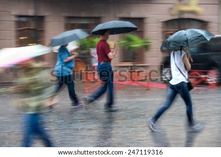 Group of people walking down the street in a rainy day in motion blur