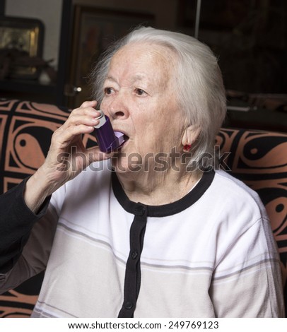 Old woman with asthma inhaler at home