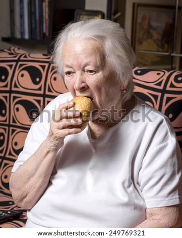 Old woman eating  bread at home