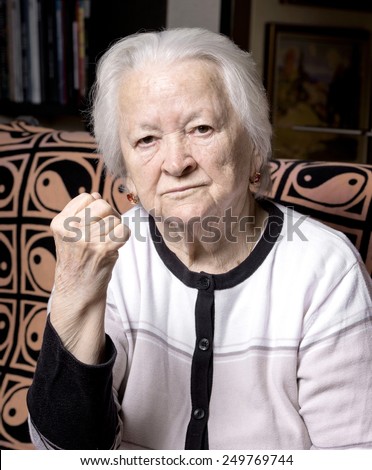 Portrait of old woman in angry gesture at home