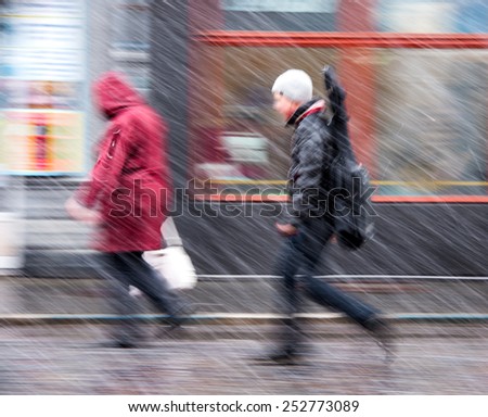 People walking down the street in a snowy winter day in motion blur