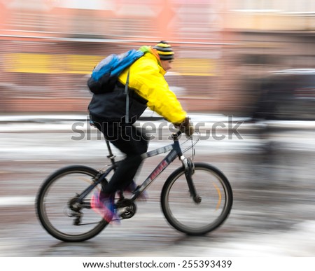 Man on bicycle in the city in a winter day. Intentional motion blur