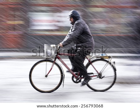 Man on bicycle in the city in snowy winter day.  Intentional motion blur