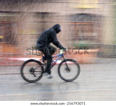 Man on bicycle in the city in snowy winter day.  Intentional motion blur