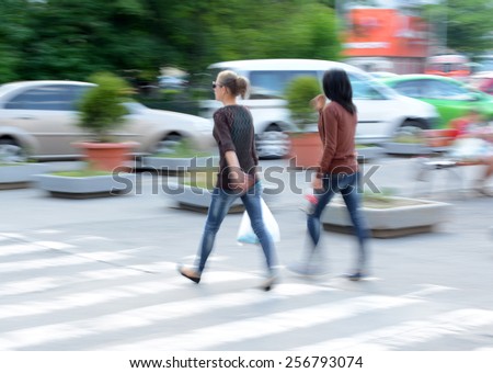 Busy city street women on zebra crossing in motion blur