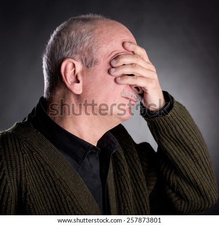 Pain, headache. Elderly man covers his face with hand