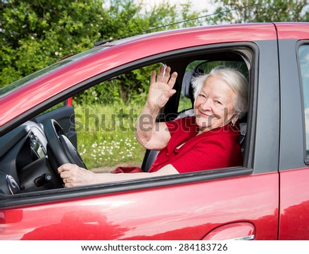Smiling old woman sitting inside the car