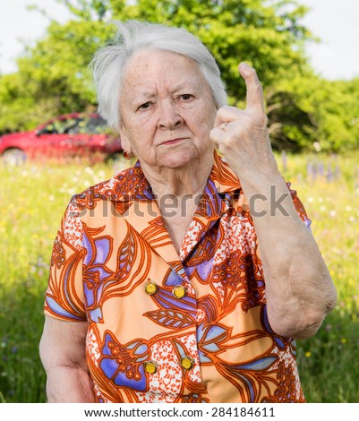 Old woman in angry gesture protecting her garden