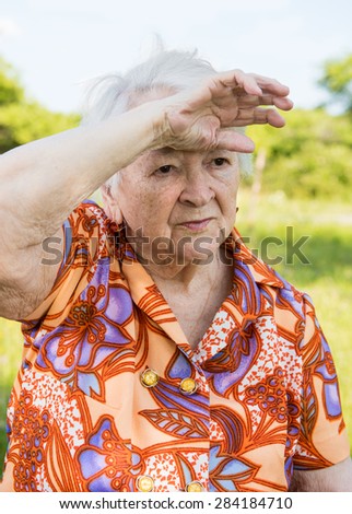 Tired sad old woman on nature background