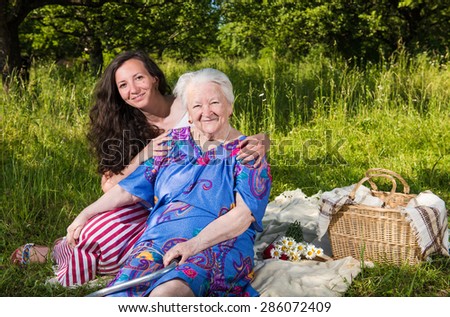 Smiling grandmother with granddaughter resting in the park