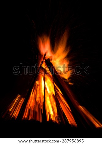 Big bonfire against dark night sky. Fire flames on black background. Zoom effect