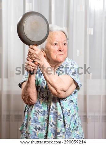 Angry old woman with a pan at home
