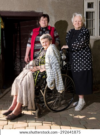 Old woman in wheel chair with daughter and sister outdoors