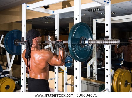 Muscular handsome bodybuilder working out in gym with barbell