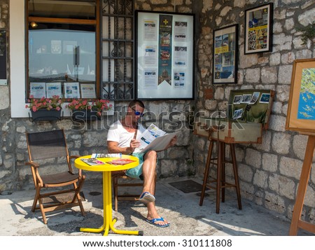 SIBENIK, CROATIA - AUGUST10, 2015: Young man reading proposals of tour operator in Sibenic, Croatia.Sibenic is a popular touristic city in Croatia