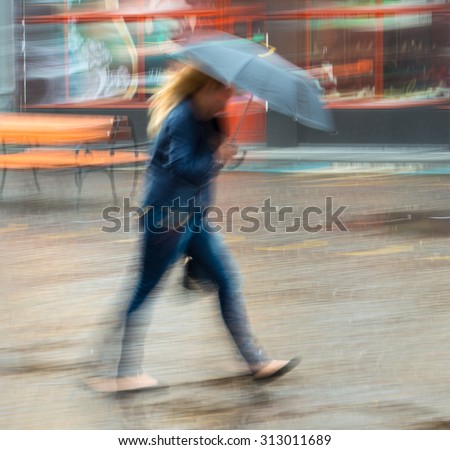 Woman walking down the street in a rainy day in motion blur