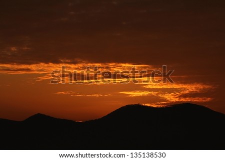 Dark orange sunrise with distant hills