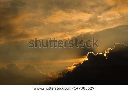 Sun peaking over a dark cloud