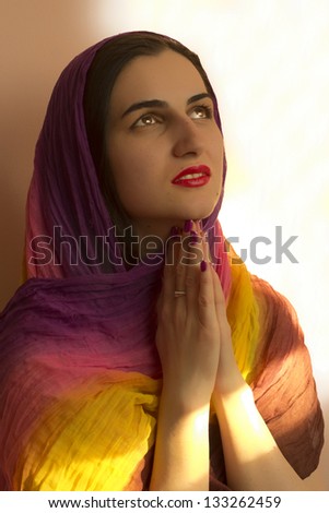 Beauty girl portrait, young fresh woman, face.  Praying, praying hands, a colorful scarf on her head.