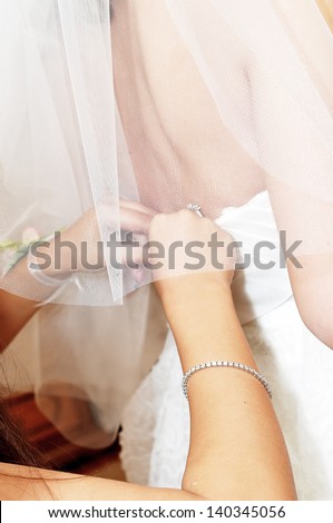 bridesmaid helping bride to get dressed before the wedding