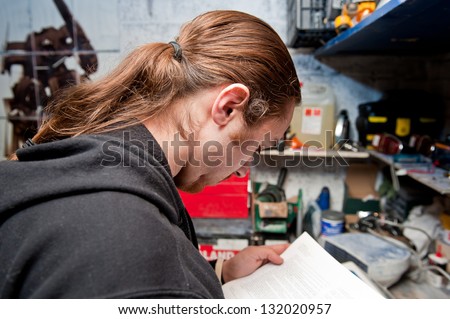 A man reads instructions before commencing maintenance work on a car in his garage