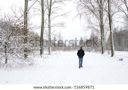Young man walking in snowy forest