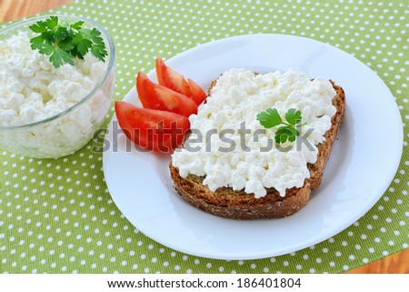 Cottage cheese on brown bread with tomatoes on plate.