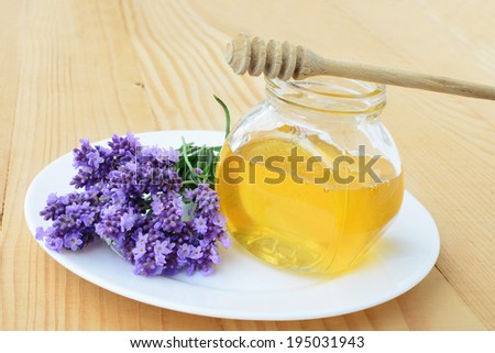 Herbal honey in jar with fresh flower - sweet food on wooden background.