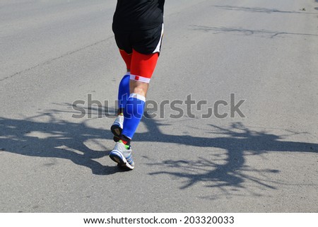 Legs of a male jogger running along the street.